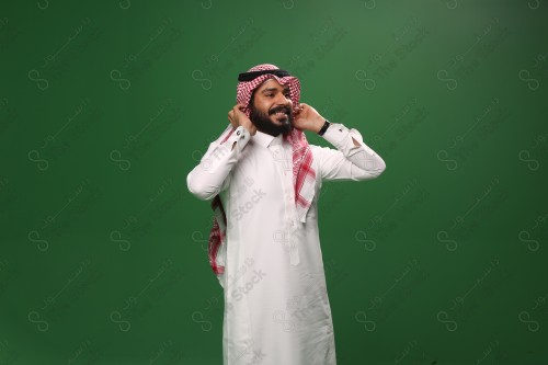 بورتريه رجل سعودي يرتدي الزي السعودي التقليدي يعدل شماغه