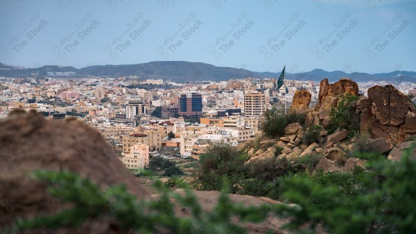 لقطة جوية لمدينة أبها وسط الطبيعة الخضراء وتظهر السماء صافية نهارًا، الطبيعة في السعودية