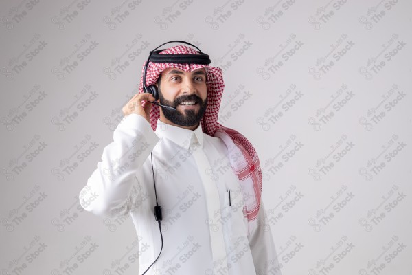 بورتريه رجل سعودي يلبس سماعة الرأس ويقوم بالتواصل عبر السماعة - خدمة العملاء ، مكالمة هاتفية