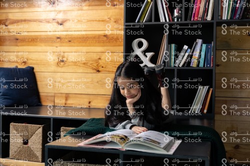 A Saudi girl browsing a book and enjoying reading in the middle of the library