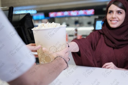 A Saudi girl wearing an abaya buys popcorn from the food court in the cinema