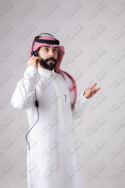 بورتريه رجل سعودي يلبس سماعة الرأس ويقوم بالتواصل عبر السماعة - خدمة العملاء ، مكالمة هاتفية