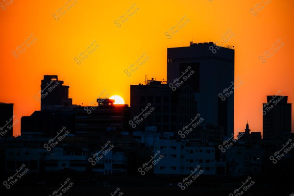 Sunset behind the city skyline with an orange sky and dark buildings in the foreground.