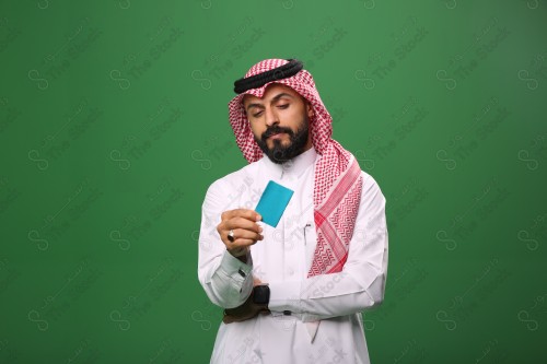 بورتريه رجل سعودي على خلفية خضراء محتار يحمل بطاقة الصرافة