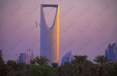 A shot showing the Kingdom Tower, one of the buildings and landmarks in the city of Riyadh, The cloudy sky appears orange at sunset.