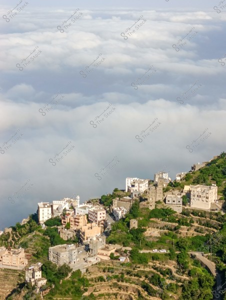 Aerial view of a mountainous area with a village overlooking a sea of clouds. The houses are built on the mountain with a traditional design, surrounded by lush greenery. The road connecting the houses is visible, with terraced land suitable for agriculture.