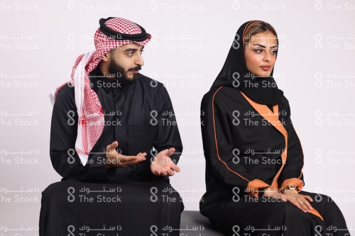 بورتريه رجل سعودي يرتدي الزي السعودي التقليدي يتناقش مع امرأة سعودية ترتدي الحجاب بينما هي تصد عنه ، شاب وفتاة يتناقشون