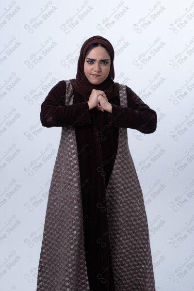 A young Saudi woman wearing an abaya and hijab, looking angry