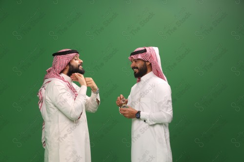 رجل سعودي يرتدي الزي السعودي التقليدي يطيب ضيفه بالدهن عود في أحد المناسبات