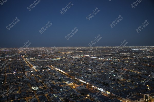 Night view of a large city with streetlights and building lights. The sky is dark, and the city is covered in bright lights stretching as far as the eye can see.
