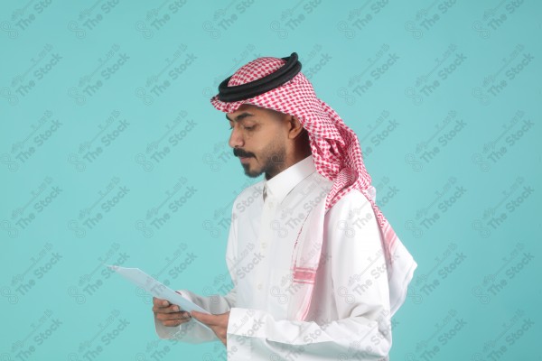 رجل سعودي يرتدي الزي السعودي يمسك بالاوراق،  يتحدث ويشرح فكرة العمل، اعمال مكتبية