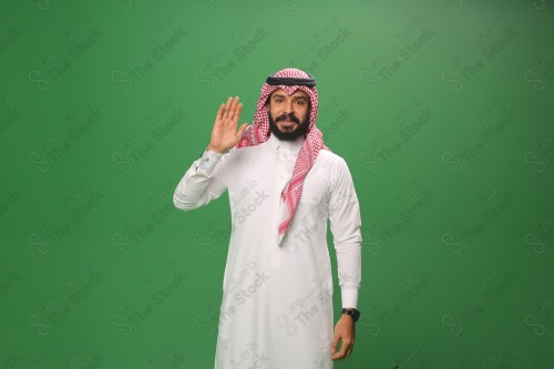 بورتريه رجل سعودي يرتدي الزي السعودي التقليدي يُلقي التحيّة على أحدهم