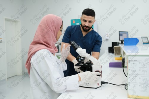 Saudi doctor in a hospital works in a laboratory, a medical team uses a microscope to examine a blood sample, and works in the field of health, providing medical consultations and medical health services.