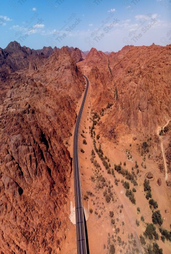 Overhead shot of a road in the middle of a group of rocky mountains.