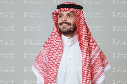 شاب سعودي مبتسم يرتدي الزي السعودي التقليدي تظهر على محياه السعادة