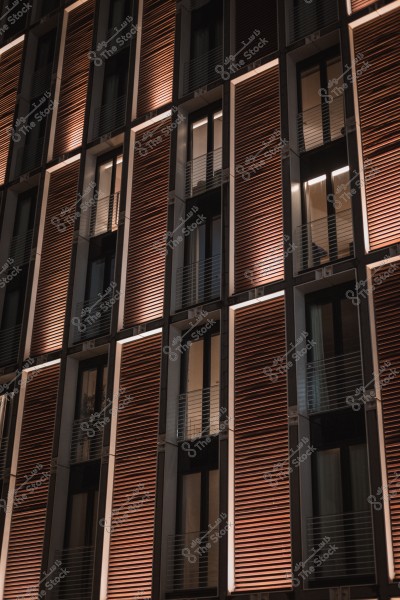 Modern building facade with large windows and neatly arranged wooden shutters.