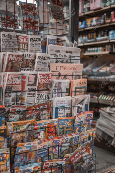 A display showing a rack filled with newspapers and magazines at a newsstand.