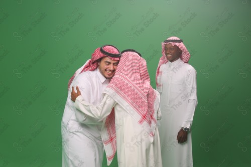 Portrait  Saudis men in traditional uniform on a green background shaking hands smiling, sad, angry, memorial photos, documenting a happy moment.