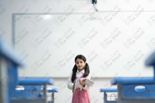 A Saudi student wears a school uniform and does different interactions and shows the tables in the classroom