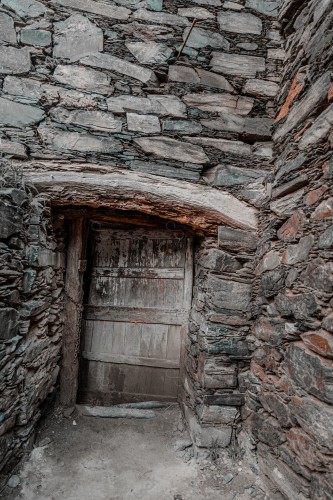 A stone-built building with a wooden door in the middle of the Rijal Almaa heritage village in the Asir region