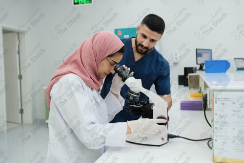 Saudi doctor in a hospital works in a laboratory, a medical team uses a microscope to examine a blood sample, and works in the field of health, providing medical consultations and medical health services.