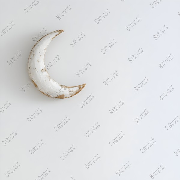 An image of a crescent-shaped sculpture covered with white paint, weathered to give it a worn appearance with brown edging. The crescent stands out against a simple white background.