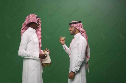 رجل سعودي يرتدي الزي السعودي التقليدي يقدم القهوة السعودية لضيفه في إحدى المناسبات