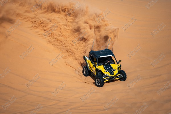 An image of a yellow dune buggy speeding across orange sand dunes, kicking up a cloud of flying sand behind it. The buggy has a black roof and large wheels, driven by a person wearing a helmet and sunglasses.