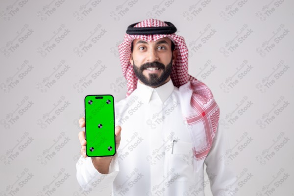 Portrait of a Saudi man holding a phone, pointing at the phone and making different expressions - green screen