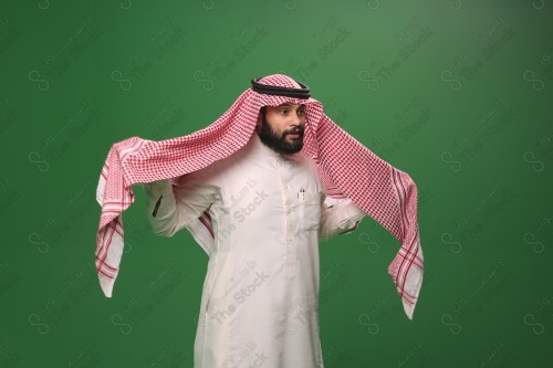 بورتريه رجل سعودي يرتدي الزي الرسمي التقليدي على خلفية خضراء يقوم بعمل اشارات بيديه وهو مبتسم ، حزين، غاضب، صور تذكارية ، توثيق لحظة سعيدة