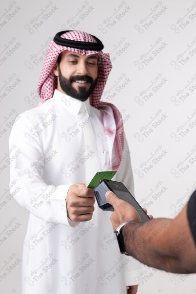 Portrait of a Saudi man holding a card and making automatic payments on a white background