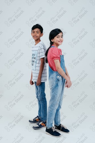 A boy and a girl standing proud and confident on a white background, different facial expressions and hands.