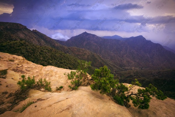 Aerial shot of a series of rocky mountains at sunset and the clouds overlapping between them, nature in Saudi Arabia, sunset