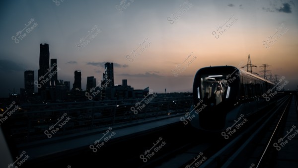 A modern metro train moving on the track at sunset with city skyline and tall buildings in the background.