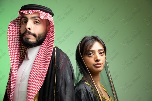 رجل سعودي يرتدي الزي السعودي وامرأه سعودية ترتدي المخنق والزي السعودي التقليدي الشعبي للمناسبات والإحتفالات الوطنية على خلفية خضراء