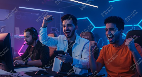 Three young men sitting in front of computer screens inside a gaming room illuminated with blue and purple neon lights. The young man on the left is wearing black headphones, focusing on the screen. The young man in the middle is wearing a white jacket and holding a mobile phone, appearing happy and excited. The young man on the right is wearing an orange shirt and also looks happy and enthusiastic.