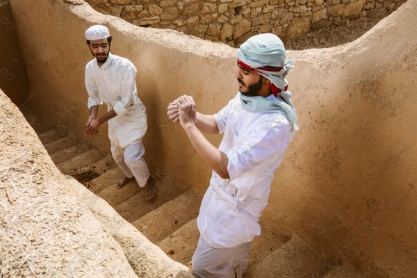 لقطة لرجلان سعوديان يعملان في بناء البيت قديم يرتدون الزي السعودي التقليدي الذي يمثل التراث الشعبي ، يوم التأسيس، الثقافة السعودية