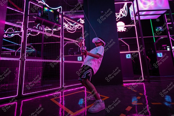 شاب يرتدي نظارة واقع افتراضي ويمسك بذراع التحكم في بيئة مليئة بالأضواء النيونية الوردية.