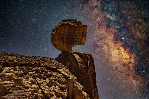 Night shot to a Rocky Mountain in the Saudi deserts, showing the Milky Way galaxy in the sky, a group of rocky mountains in the desert