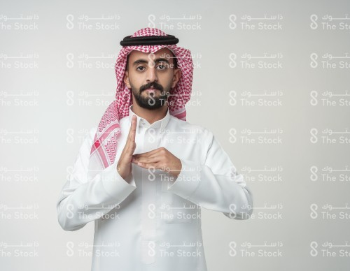 رجل سعودي يرتدي الزي السعودي الرسمي يشير بيده بحرف من حروف لغة الإشارة