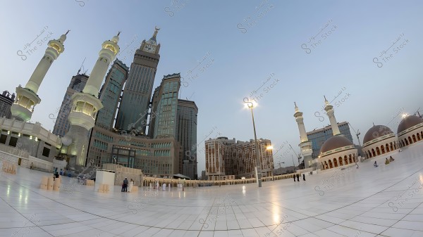 صورة لبرج ساعة مكة في المملكة العربية السعودية مع المسجد الحرام في المقدمة خلال وقت الغروب.