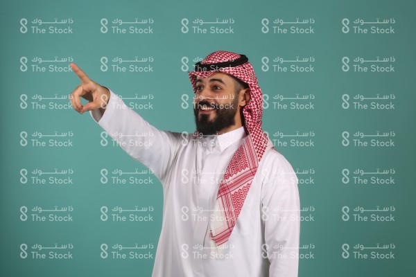 تفاعل شاب سعودي سعيد ويقوم بالإشارة للأعلى ويرتدي الزي السعودي