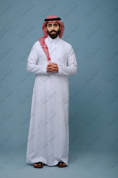 Portrait of a Saudi young man wearing the Saudi dress, and happiness and joy appearing on his features, against a heavenly background