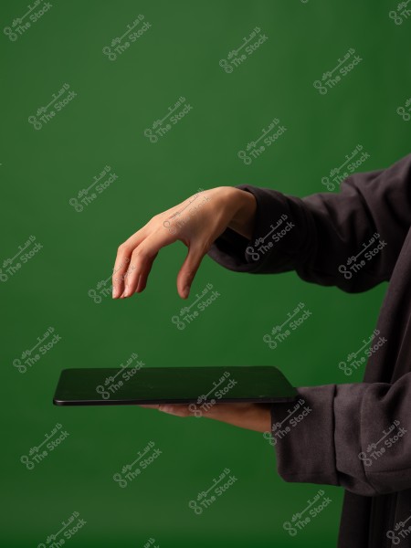 يد تحمل جهازًا لوحيًا مع خلفية خضراء.