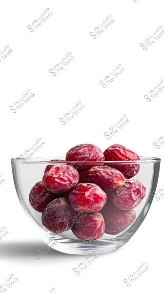 An image of a clear glass bowl containing several dark red dates. The dates appear fresh and shiny, and the bowl is set against a white background.