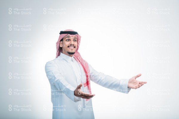 رجل سعودي ، يرتدي الزي الرسمي السعودي ، على خلفية بيضاء ، يتفاعل بإشارات تعبيرية بيديه ، تعابير وجه تدل على الفرح والسعادة ، الفرحة برؤية شخص عزيز