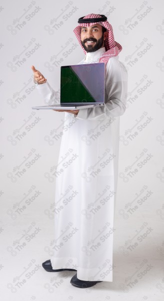 Portrait of a Saudi man holding a laptop, pointing at the laptop and making different expressions - green screen