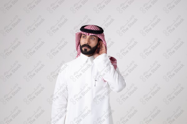 بورتريه رجل سعودي يقف على خلفية بيضاء ويشير بيده اتجاه معين