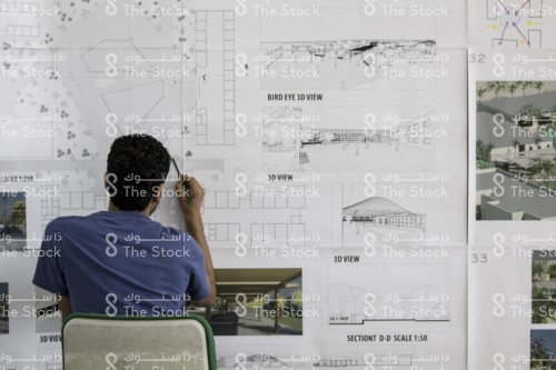 شاب سعودي يرسم مخططات معمارية وخرائط مباني، طالب في كلية الهندسة يعمل على المشاريع المعمارية, مخطط معماري قيد الانشاء