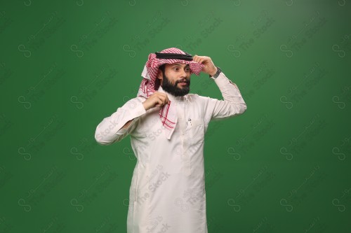 بورتريه رجل سعودي يرتدي الزي الرسمي التقليدي على خلفية خضراء يقوم بعمل اشارات بيديه وهو مبتسم ، حزين، غاضب، صور تذكارية ، توثيق لحظة سعيدة